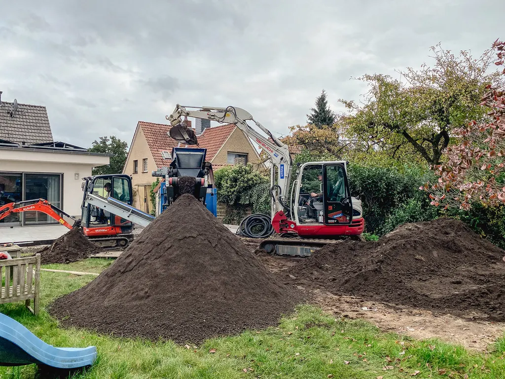 Bodenaushub auf einem Grundstück, im Hintergrund Bagger